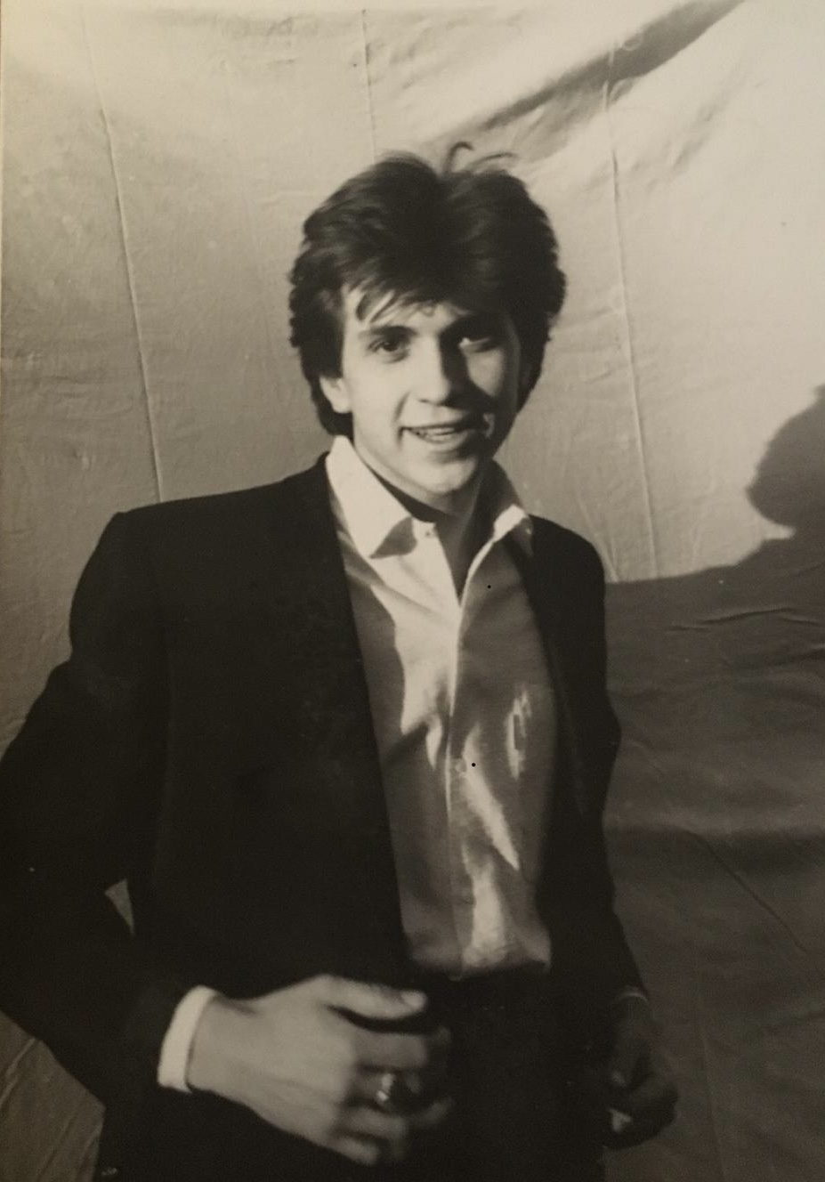 Frédéric Roulette jeune, en veste sombre et chemise blanche ouverte, devant une toile tendue